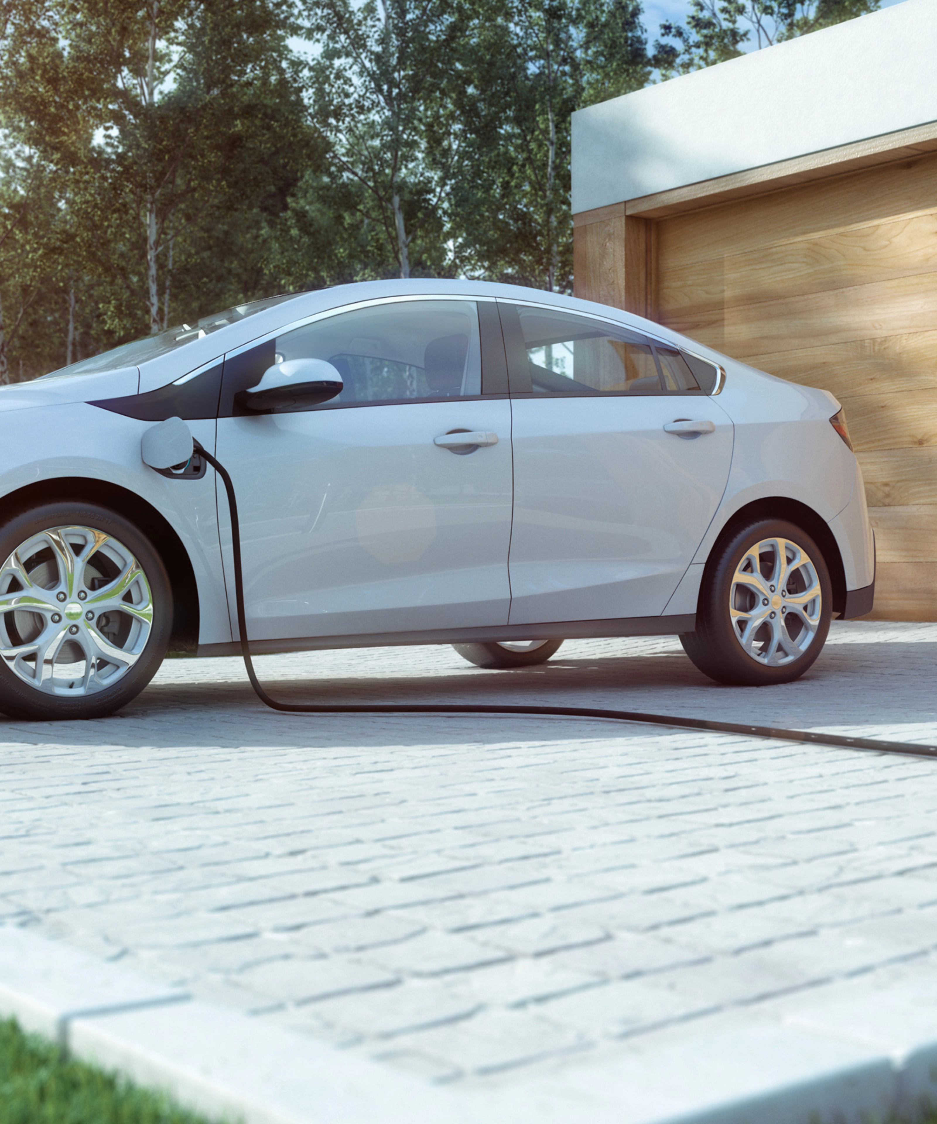 An electric car is charging in front of a modern house with a wooden garage door.