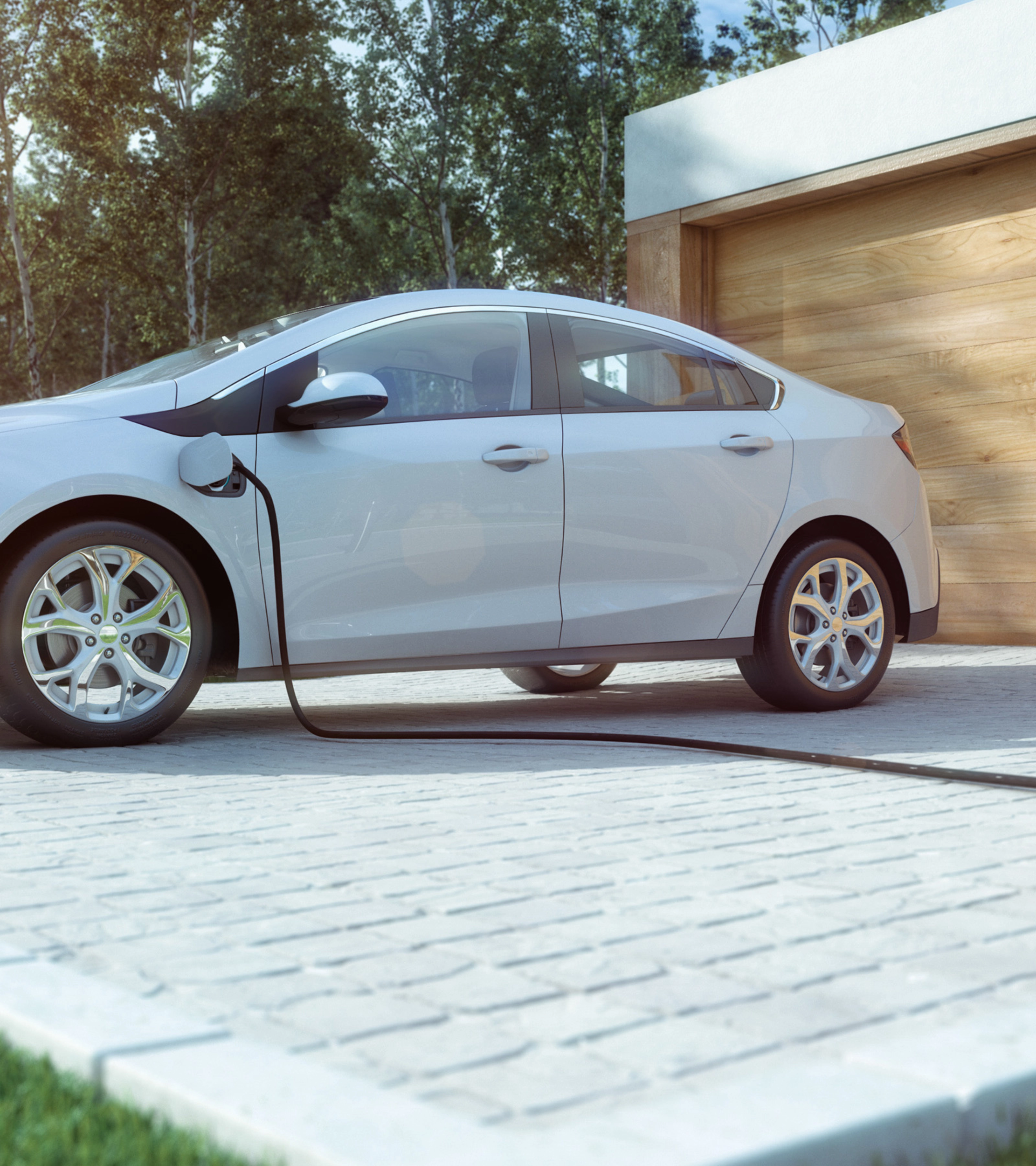 An electric car is charging in front of a modern house with a wooden garage door.